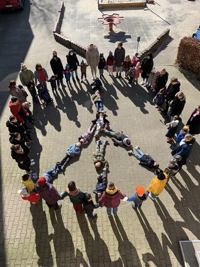 Der Kindergarten macht mit allen Kindern und Betreuern ein Friedenszeichen